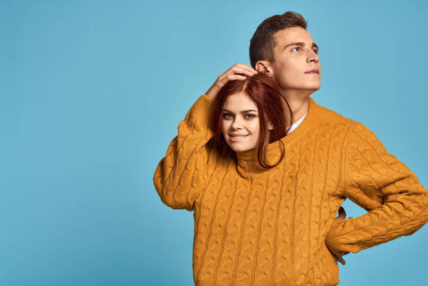 Verliebtes Paar in gelbem Pullover posiert vor blauem Hintergrund - Foto, Bild