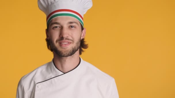 Portrait of professional italian chef in uniform joyfully smiling looking in camera over colorful background. Copy space - Footage, Video