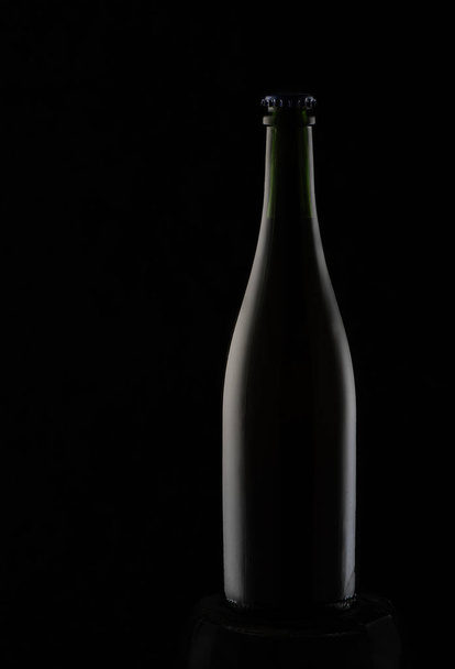 Black bottle on a black background with highlights - Foto, Imagem