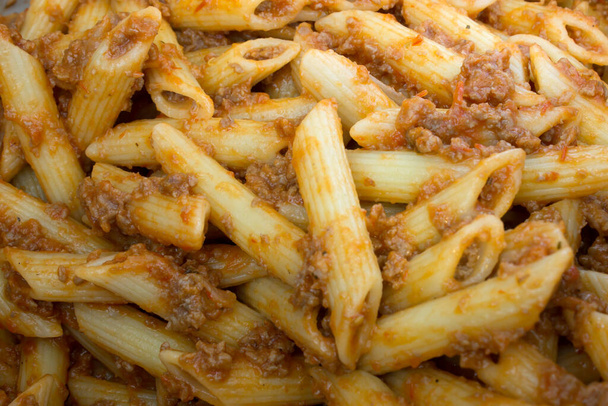 This is a photograph of Penne Pasta covered in Tomato sauce and ground beef - Photo, Image