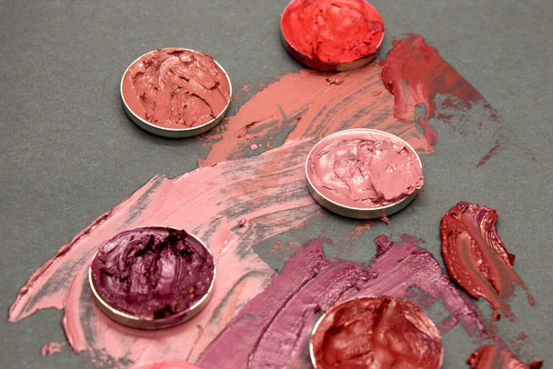 tinten van rode, roze en paarse lippenstift stalen op een zwarte achtergrond - Foto, afbeelding