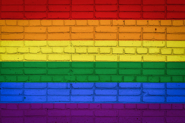 Флаг ЛГБТ, изображающий цвета краски на старой кирпичной стене. Флаг на фоне кирпичной стены. - Фото, изображение