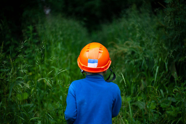 Child in a protective helmet. Construction helmet on the boy's head. The schoolboy leaves for the forest. - Φωτογραφία, εικόνα