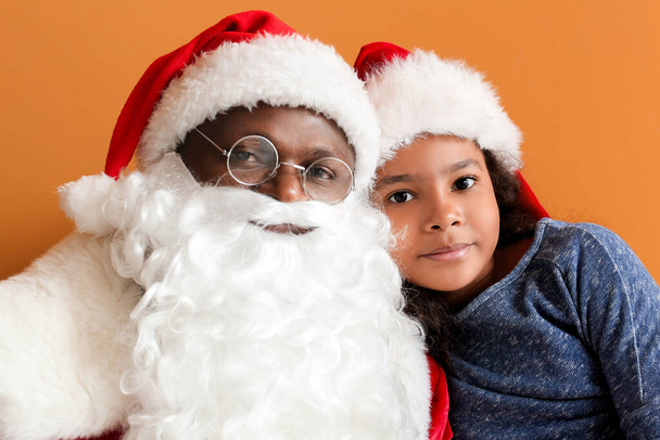 Afro-americano Papai Noel com linda menina no fundo de cor - Foto, Imagem