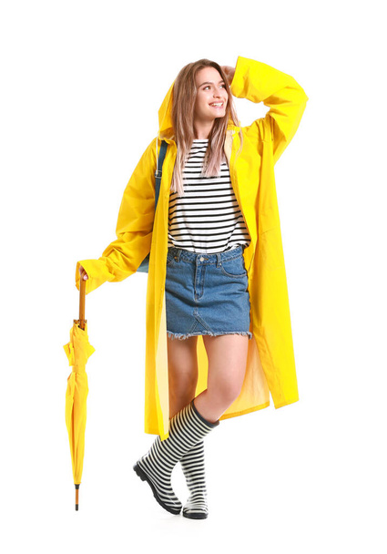 Hermosa joven en impermeable y con paraguas sobre fondo blanco - Foto, imagen