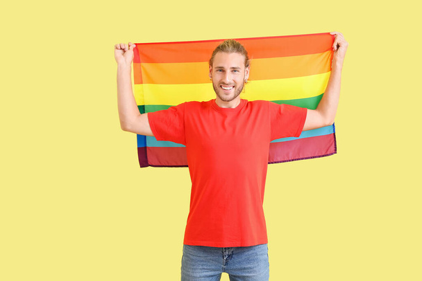 Молодой человек с флагом ЛГБТ на цветном фоне - Фото, изображение