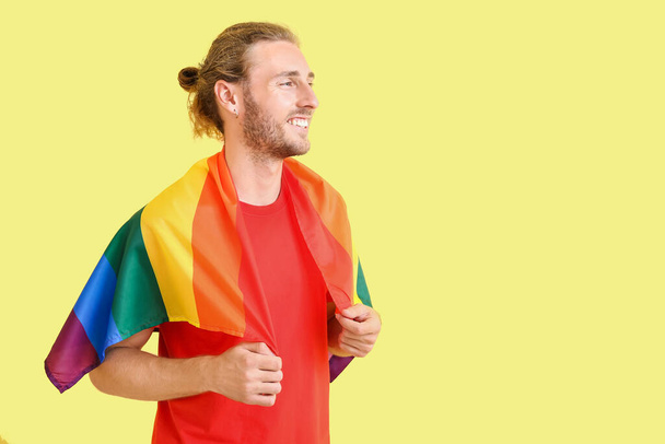 Young man with LGBT flag on color background - Valokuva, kuva
