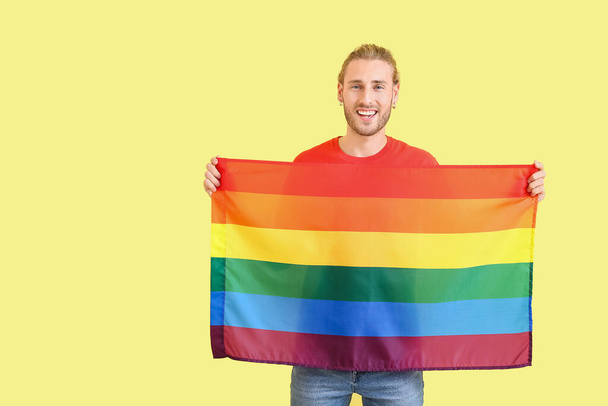 Young man with LGBT flag on color background - Photo, Image