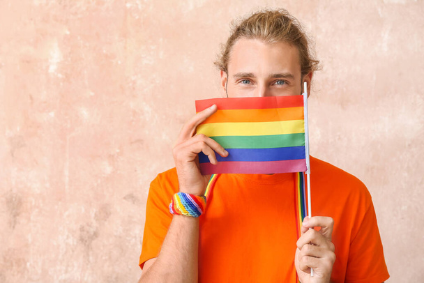 Nuori mies, jolla on LGBT-lippu väritaustalla - Valokuva, kuva