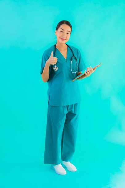 Retrato hermosa joven asiática médico mujer con tablero de papel vacío para el espacio de copia sobre fondo azul aislado - Salud en el hospital y el concepto de clínica
 - Foto, imagen