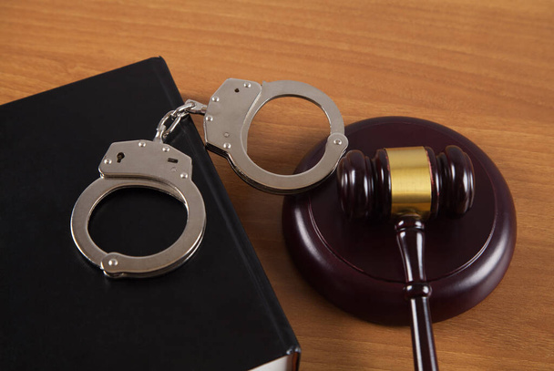 Gavel and handcuffs legal book on wooden table. - Photo, Image