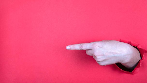 Δάχτυλο χέρι δείχνει στο κόκκινο φόντο. Ελεύθερος χώρος για κείμενο και αντίγραφο χώρου - Φωτογραφία, εικόνα
