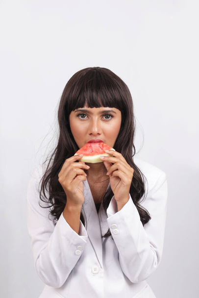 eating watermelon beautiful latin woman doctor. Woman eating watermelon. Studio isolated portrait - Фото, зображення