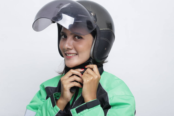 vrouw met behulp van helm motorfiets holding smartphone. jong aziatische vrouw het dragen van helm voor rijden een motorfiets. - Foto, afbeelding