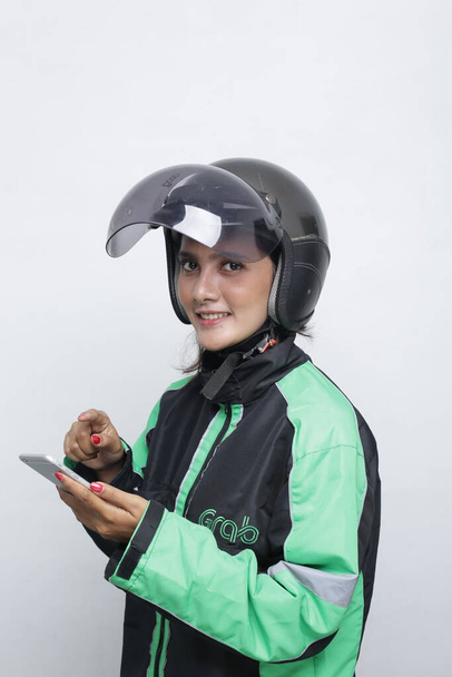 nainen käyttää kypärä moottoripyörä tilalla älypuhelin. Nuori aasialainen nainen yllään kypärä ennen ratsastaa moottoripyörä. - Valokuva, kuva