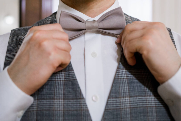 man puts on a bow tie with his hands - Фото, зображення