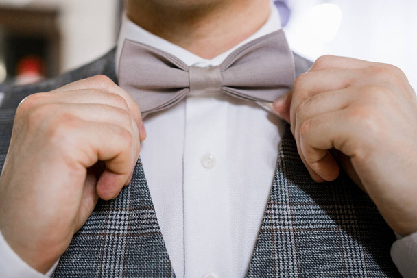 man puts on a bow tie with his hands - Φωτογραφία, εικόνα