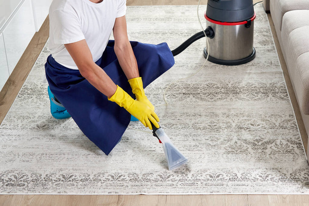 Muž úklid koberec v obývacím pokoji pomocí vysavače doma. Koncept úklidové služby - Fotografie, Obrázek