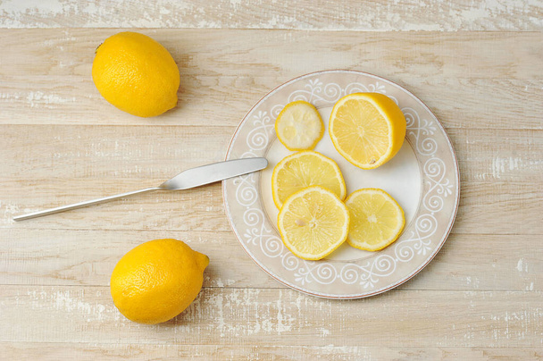 whole and sliced yellow lemons on a plate on a wooden background - top view - Foto, immagini