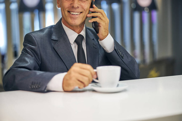 Uomo d'affari sorridente che parla su smartphone al bar - Foto, immagini