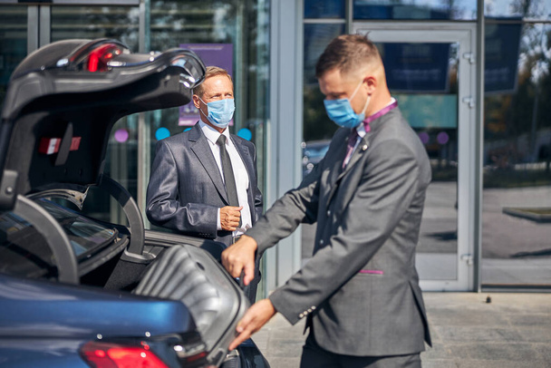 Chauffeur aidant patron avec le transport pendant la pandémie - Photo, image