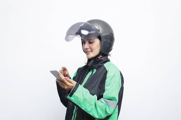 happy female using motorbike helmet with smartphone in hand - Фото, изображение
