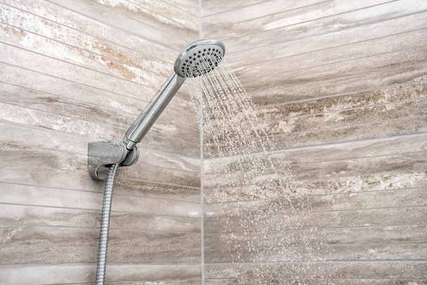 A falra szerelt zuhanyból víz folyik a fürdőszobába, közelről. Modern belső és belső dekoráció. - Fotó, kép