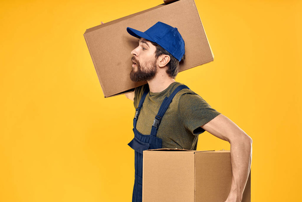 Egy ember munkaformában egy doboz betöltő szerszámok sárga háttér - Fotó, kép