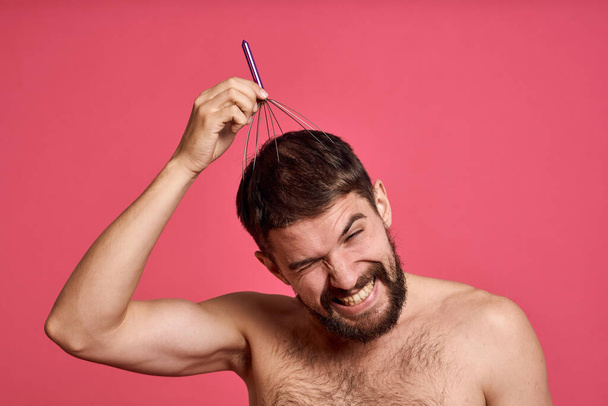 man met hoofd massager ontspannen lichaamsverzorging roze achtergrond - Foto, afbeelding