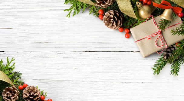 Рождественская композиция из еловых ветвей, конусов и подарочной коробки на белом деревянном фоне - Фото, изображение