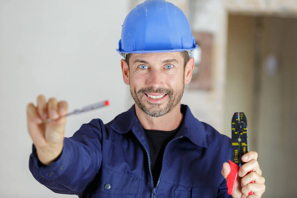 portrait of a happy young male builder showing tools - Fotó, kép