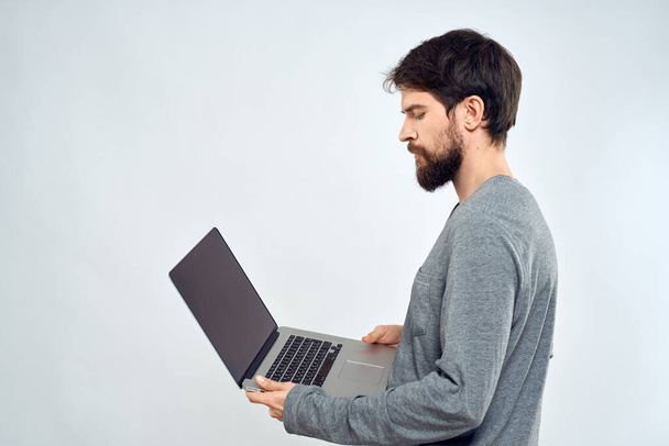 Un homme dans un pull gris avec un ordinateur portable mains style de vie technologie communication internet travail - Photo, image