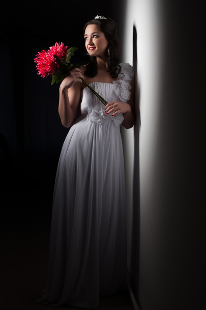bruid in een witte jurk in een bundel van licht - Foto, afbeelding