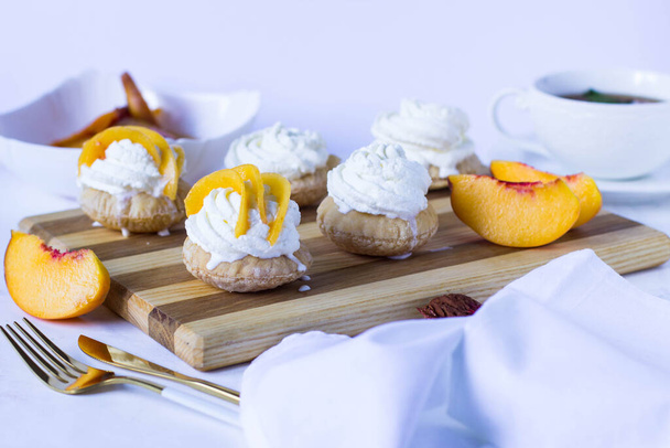 Puff leivonnaiset kakku kermavaahtoa ja persikka puulaudalla - Valokuva, kuva