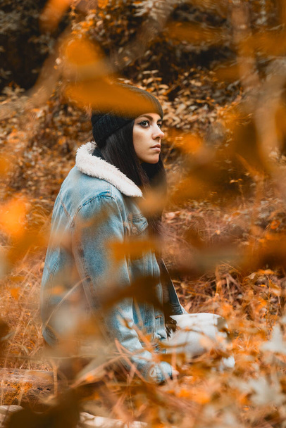 Jovem mulher olhando através de uma floresta de cores de outono com roupas de estação - Foto, Imagem