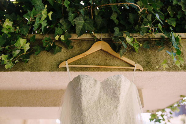 Wooden hanger on a canopy with a white bridesmaid dress. - Photo, Image