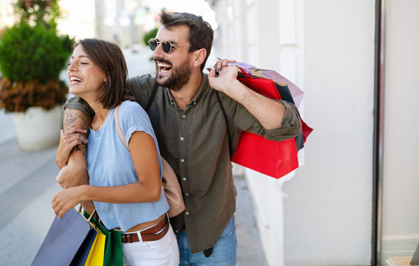 Young attractive happy couple with shopping bags outdoors in city - Photo, image