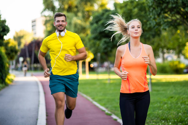 Jeune couple fait du jogging sur piste de course dans le parc. - Photo, image
