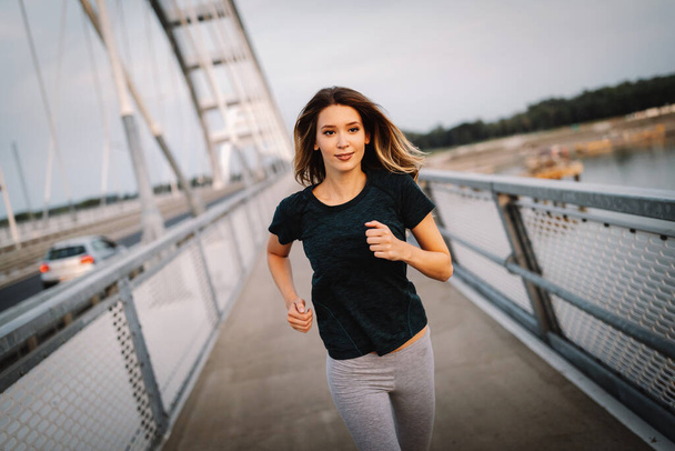 Beautiful fit happy jogger woman crossing bridge - Fotó, kép