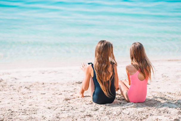 Δύο χαρούμενα κοριτσάκια διασκεδάζουν πολύ στην τροπική παραλία παίζοντας μαζί. - Φωτογραφία, εικόνα