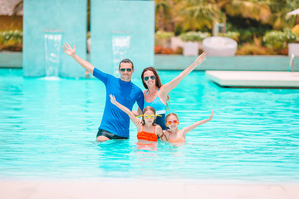 Familia feliz de cuatro en la piscina al aire libre - Foto, imagen