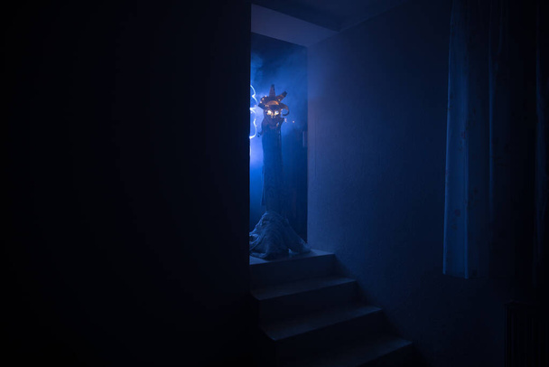 Silhouet van een onbekende schaduwfiguur op een deur door een gesloten glazen deur. Spookachtig silhouet meisje 's nachts met rook op de achtergrond - Foto, afbeelding
