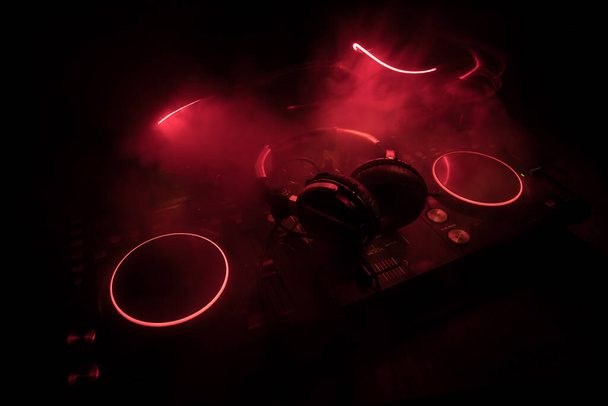 Klub zene koncepció. DJ konzol DJ-keverő asztal sötétben, színes fénnyel. Mixer berendezések szórakoztató DJ állomás. Szelektív fókusz - Fotó, kép