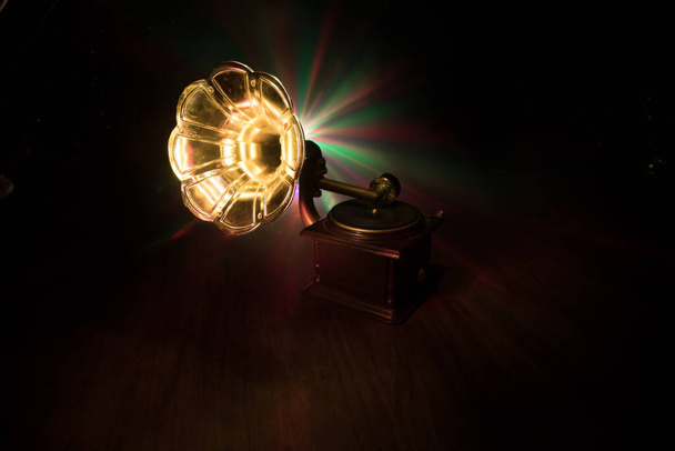 Concept musical. Vieux gramophone sur fond sombre. Gramophone rétro avec disque sur table en bois avec rétroéclairage tonique. Concentration sélective - Photo, image