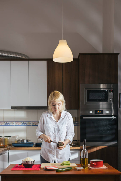 Female chef cutting avocado in a home kitchen - Foto, imagen