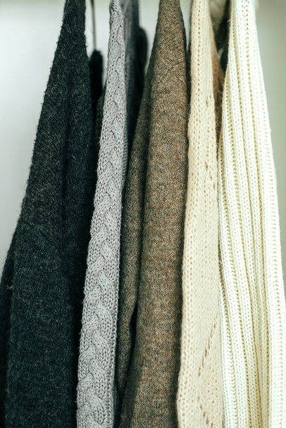 Knitted clothes sweater hanging in the closet. Cozy autumn-winter wardrobe. - Photo, Image
