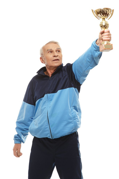 Hombre mayor en traje de entrenamiento con una taza de premio
 - Foto, imagen