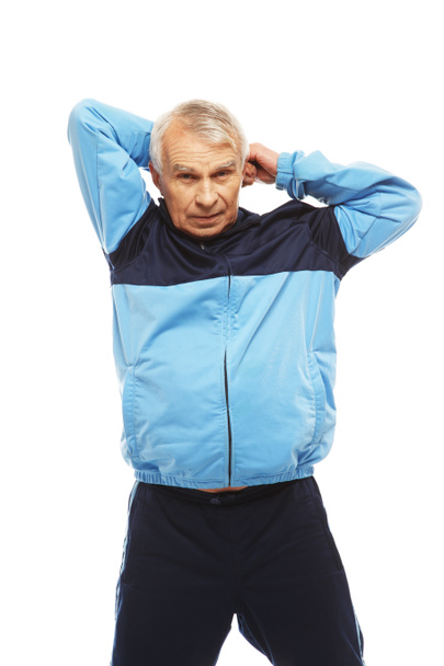Hombre mayor en traje de entrenamiento haciendo ejercicios de estiramiento de calentamiento
  - Foto, Imagen