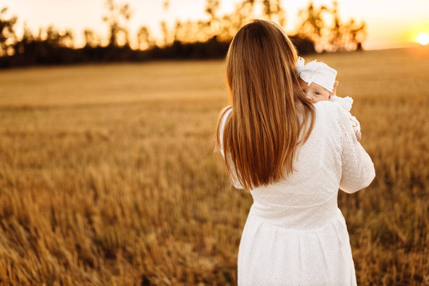 Wonderful woman with beautiful newborn baby girl walking at the field, loving mother hold in arms little daughter, enjoy happy parenting moments, parenthood and motherhood concept - Foto, immagini
