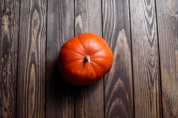 pumpkin for Halloween. Thanksgiving Day. orange ripe pumpkin lies on a dark wooden table. preparation for the holiday. - Фото, изображение